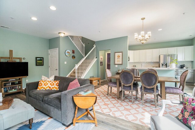 living room with light wood finished floors, a chandelier, recessed lighting, and stairway