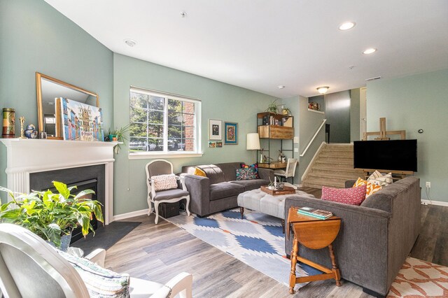 living room with stairway, recessed lighting, wood finished floors, a fireplace with flush hearth, and baseboards
