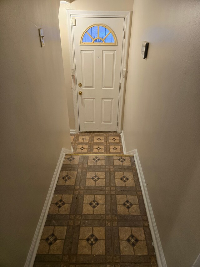 doorway to outside with baseboards and tile patterned floors