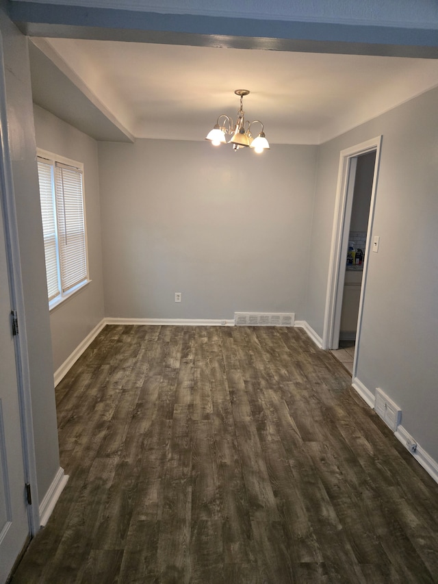 spare room with a chandelier, dark wood finished floors, and baseboards