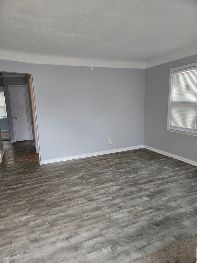 empty room featuring baseboards, dark wood finished floors, and a textured ceiling