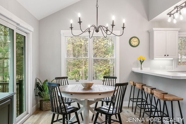 16840 Cricket Ct, Grand Haven, MI 49417 - dining area featuring a chandelier, light wood-style flooring, vaulted ceiling, and plenty of natural light