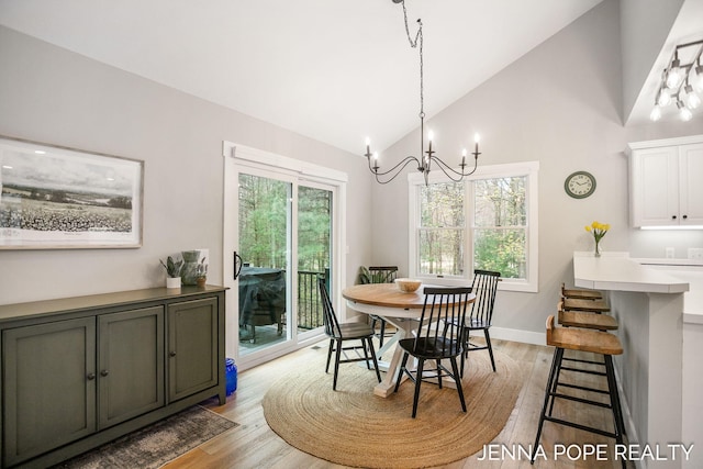 16840 Cricket Ct, Grand Haven, MI 49417 - dining space with light wood-style floors, a chandelier, high vaulted ceiling, and baseboards