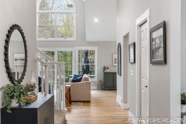 16840 Cricket Ct, Grand Haven, MI 49417 - corridor featuring a towering ceiling, light wood-style floors, and baseboards