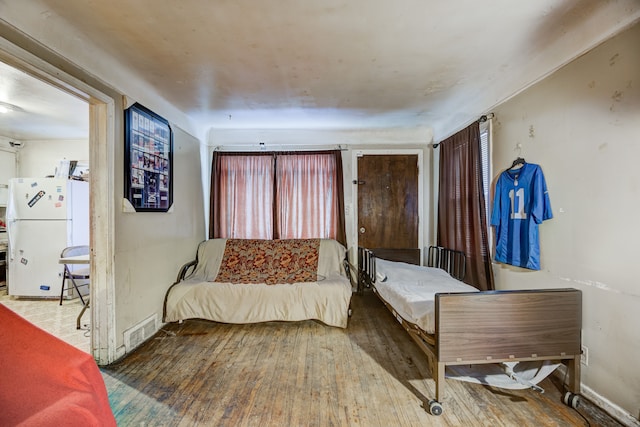 bedroom featuring freestanding refrigerator, wood finished floors, and baseboards
