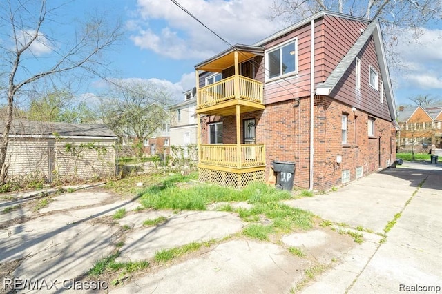 back of house featuring a balcony and brick siding