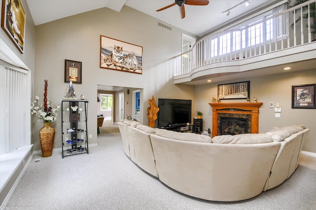 carpeted living room with high vaulted ceiling, a ceiling fan, a glass covered fireplace, and baseboards