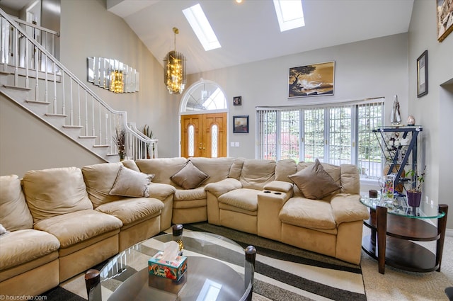 living area featuring a skylight, high vaulted ceiling, a chandelier, stairway, and carpet flooring