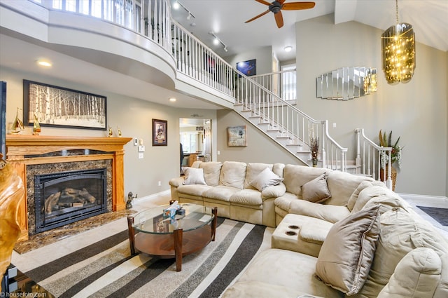 living room featuring high vaulted ceiling, a ceiling fan, stairway, a premium fireplace, and recessed lighting