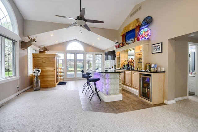 indoor bar with wine cooler, light carpet, recessed lighting, ceiling fan, and high vaulted ceiling