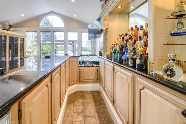 indoor bar with lofted ceiling, plenty of natural light, light stone finish floors, and recessed lighting