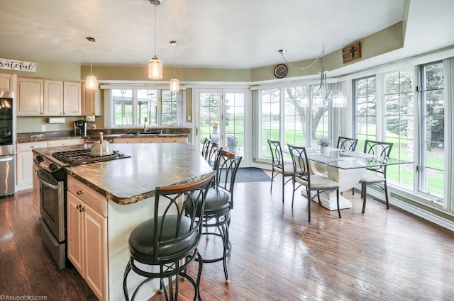kitchen with stainless steel appliances, dark countertops, a breakfast bar, dark wood-type flooring, and pendant lighting