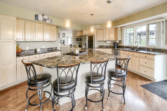 kitchen with stainless steel appliances, a sink, a center island, a kitchen breakfast bar, and light wood-style floors