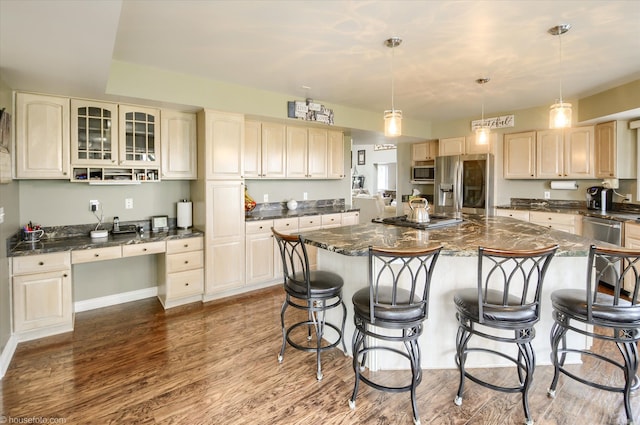 kitchen with appliances with stainless steel finishes, a breakfast bar area, light wood-style floors, a center island, and glass insert cabinets