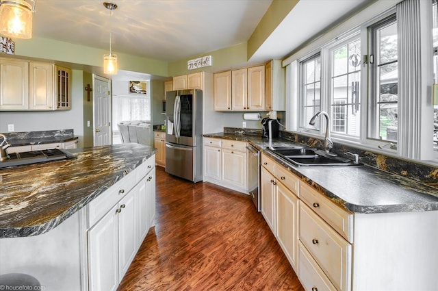 kitchen with appliances with stainless steel finishes, a sink, dark wood finished floors, and hanging light fixtures