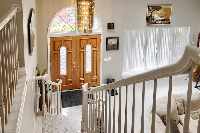 foyer featuring light carpet, a chandelier, a high ceiling, and stairs
