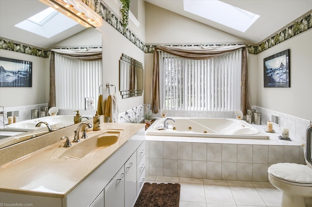 full bath with a skylight, vaulted ceiling, tile patterned flooring, a tub with jets, and vanity