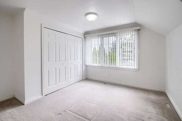 unfurnished bedroom with carpet, vaulted ceiling, baseboards, and a closet