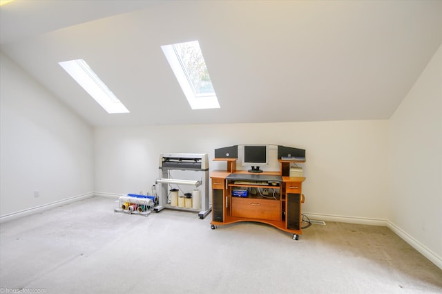 office space featuring a skylight, vaulted ceiling, light colored carpet, and baseboards