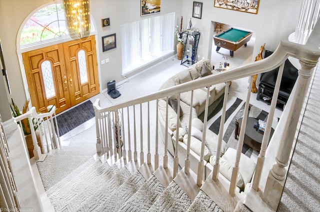 entrance foyer featuring carpet flooring, billiards, a chandelier, a towering ceiling, and stairway