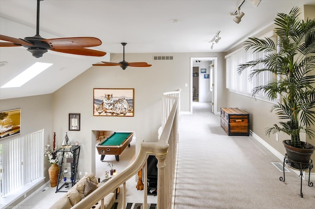 corridor featuring carpet floors, baseboards, rail lighting, and vaulted ceiling