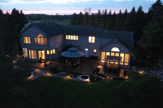 rear view of property featuring a gazebo, a patio, a yard, and a forest view