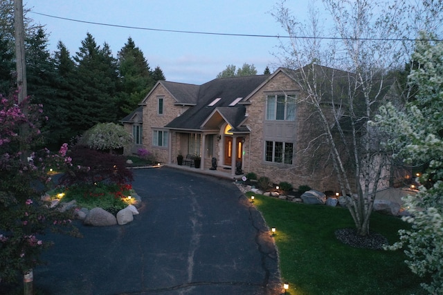 craftsman-style home with a front lawn, stone siding, and driveway