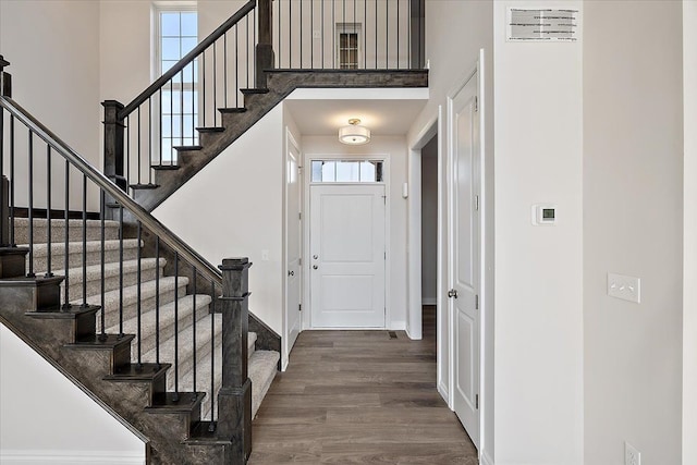 entrance foyer featuring a towering ceiling, dark wood finished floors, stairs, and baseboards