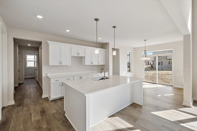 kitchen with a sink, white cabinets, wood finished floors, a center island with sink, and recessed lighting