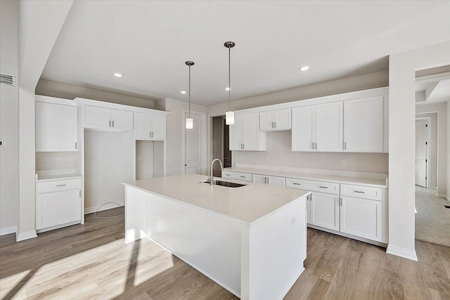 kitchen featuring a sink, light wood-type flooring, white cabinetry, and recessed lighting