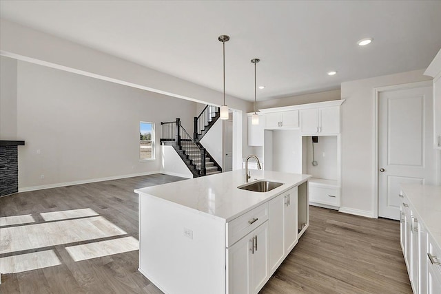 kitchen with a sink, wood finished floors, white cabinetry, hanging light fixtures, and recessed lighting