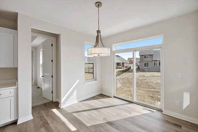 unfurnished dining area with wood finished floors and baseboards
