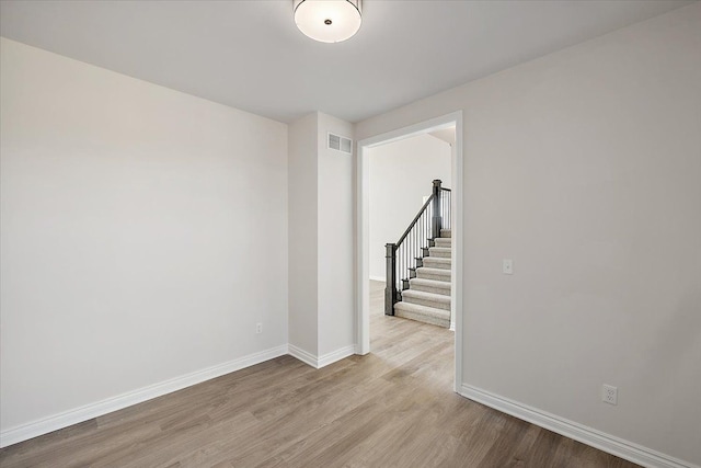 empty room with wood finished floors, baseboards, and stairway