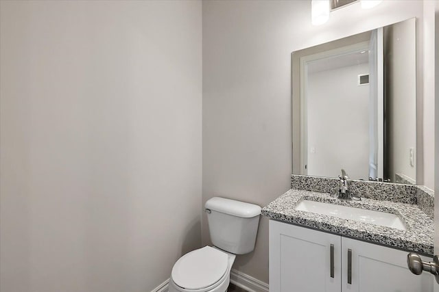 bathroom with toilet, vanity, and baseboards