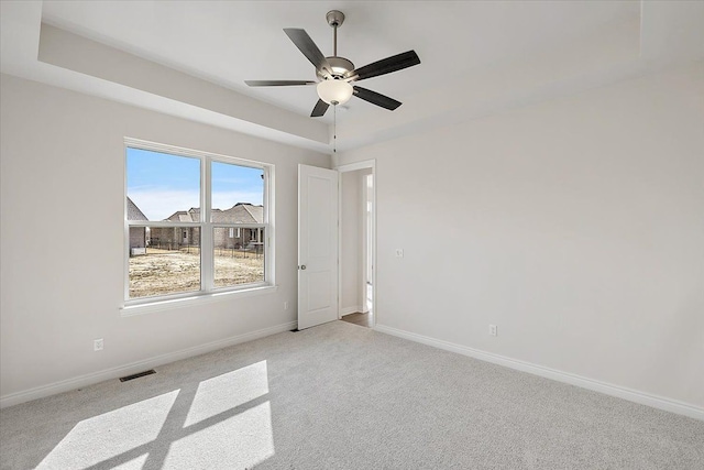 empty room featuring light colored carpet, baseboards, and a ceiling fan