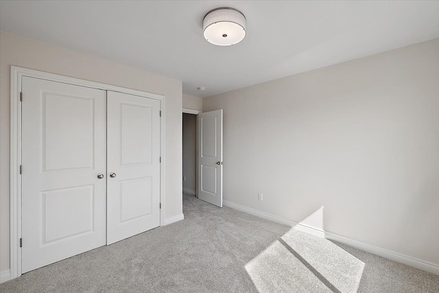 unfurnished bedroom with carpet, baseboards, and a closet