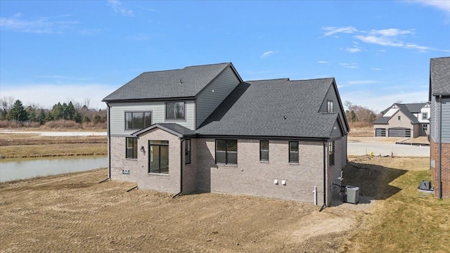 back of property featuring a shingled roof, a water view, and brick siding
