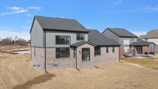 back of house with brick siding and roof with shingles