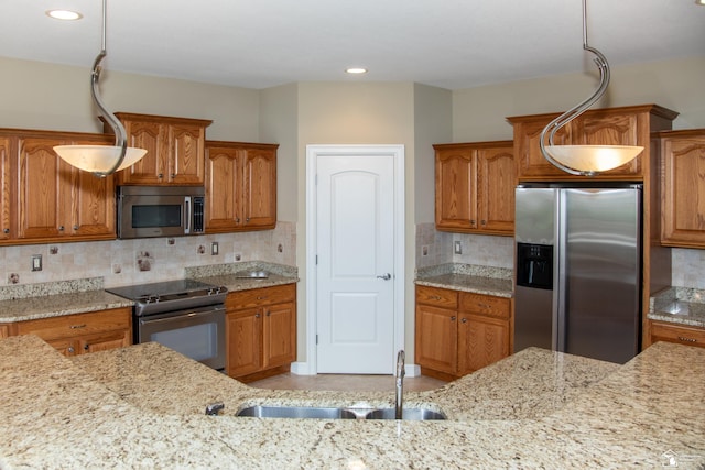 kitchen with stainless steel appliances, a sink, brown cabinetry, light stone counters, and recessed lighting