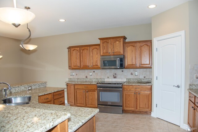 kitchen featuring appliances with stainless steel finishes, a sink, brown cabinets, and recessed lighting