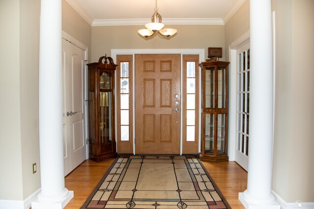 entrance foyer featuring plenty of natural light, light wood-style flooring, crown molding, and decorative columns