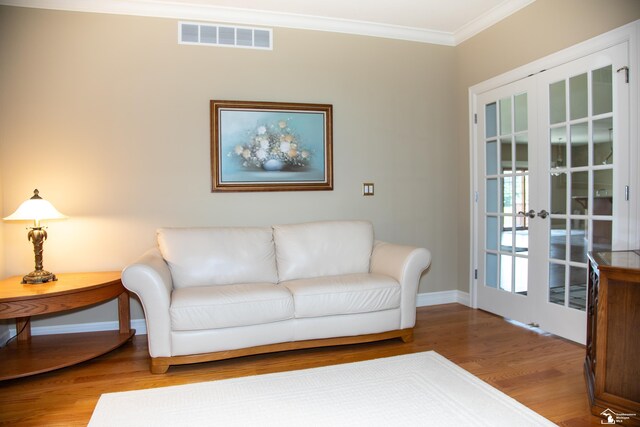living area featuring wood finished floors, crown molding, baseboards, and french doors