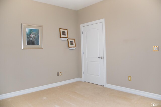 spare room featuring light carpet and baseboards