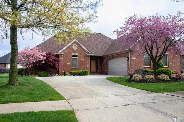 view of front of house featuring brick siding, a garage, concrete driveway, a front lawn, and roof with shingles