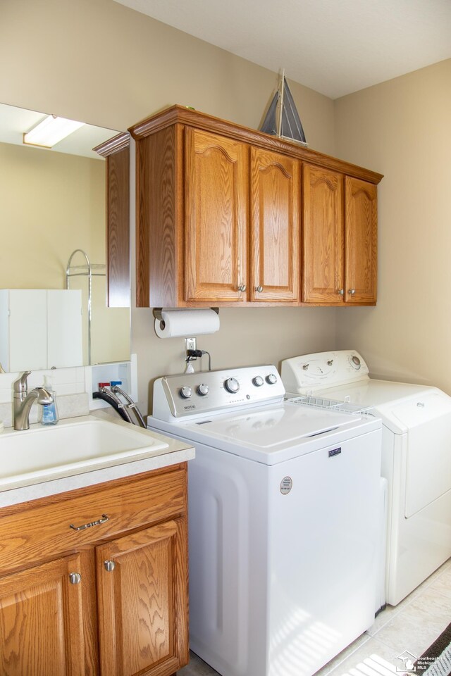 clothes washing area featuring cabinet space, washing machine and dryer, and light tile patterned floors