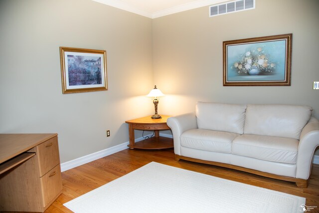 living area with ornamental molding, baseboards, and light wood finished floors