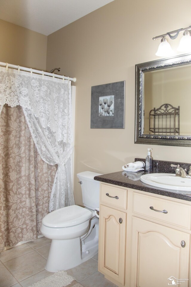 bathroom with tile patterned flooring, toilet, vanity, and curtained shower