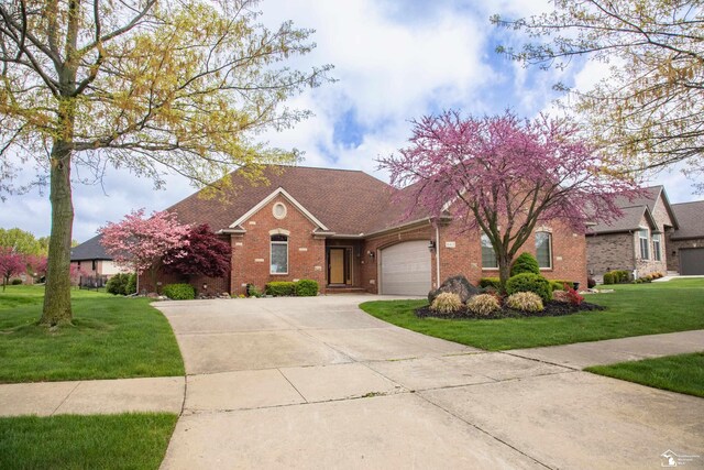 view of front of property featuring brick siding, an attached garage, concrete driveway, a front yard, and a shingled roof