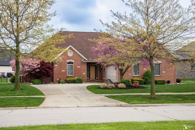 view of front of property with brick siding, driveway, and a front yard
