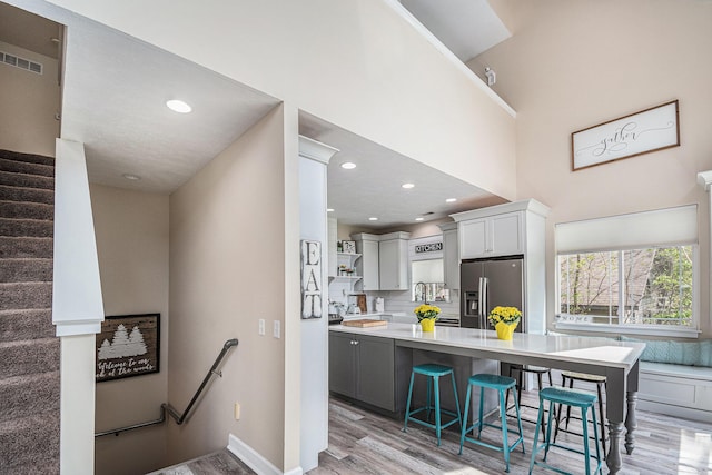 7379 Wimpole Dr NE, Belding, MI 48809 - kitchen featuring stainless steel fridge, open shelves, light wood-style flooring, light countertops, and a breakfast bar